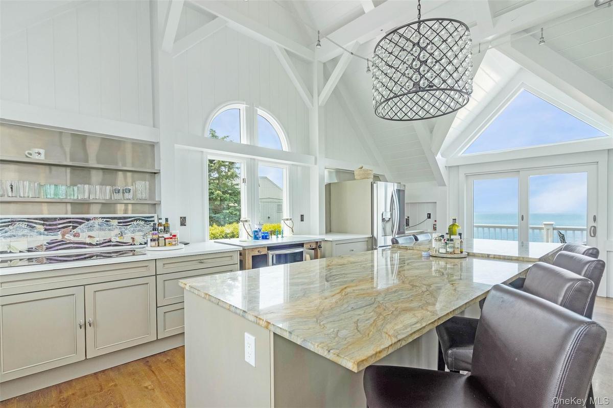 Kitchen featuring high vaulted ceiling, stainless steel fridge, a kitchen breakfast bar, plenty of natural light, and a water view
