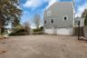 View of property exterior with a gambrel roof, driveway, stairway, and an attached garage