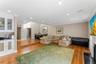 Open-concept living space featuring wood-finish flooring, a built-in wet bar with glass-front cabinetry and a dark countertop, recessed ceiling lighti
