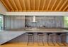 Kitchen with modern cabinets, wall chimney exhaust hood, decorative backsplash, and light stone countertops