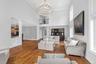 Two-story living area featuring hardwood flooring, a multi-tiered chandelier, tall arched windows, and a second-story balcony
