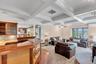 Living room featuring beam ceiling, coffered ceiling, ornamental molding, light carpet, and an AC wall unit