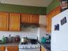 Kitchen featuring white appliances, brown cabinets, dark stone counters, under cabinet range hood, and tasteful backsplash