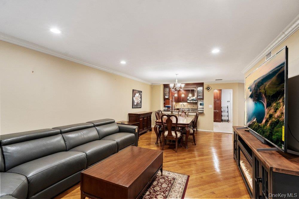 Open-concept living area with wood-finish flooring, recessed lighting, and crown molding