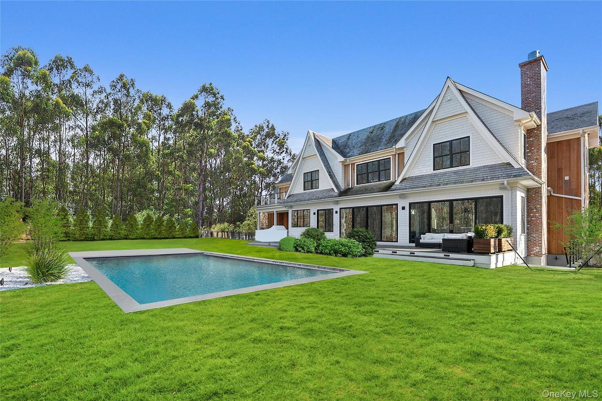 Rear view of house featuring a yard, a chimney, a patio area, an outdoor hangout area, and an outdoor pool