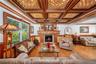 Living room featuring wainscoting, crown molding, a warm lit fireplace, coffered ceiling, and wood finished floors