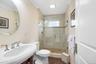 Upstairs elegant bathroom featuring a curved pedestal sink with chrome fixtures, ceramic tile shower enclosure with glass doors, white subway tile sur