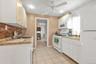 Kitchen featuring white appliances, light countertops, light tile patterned floors, ceiling fan, and white cabinetry