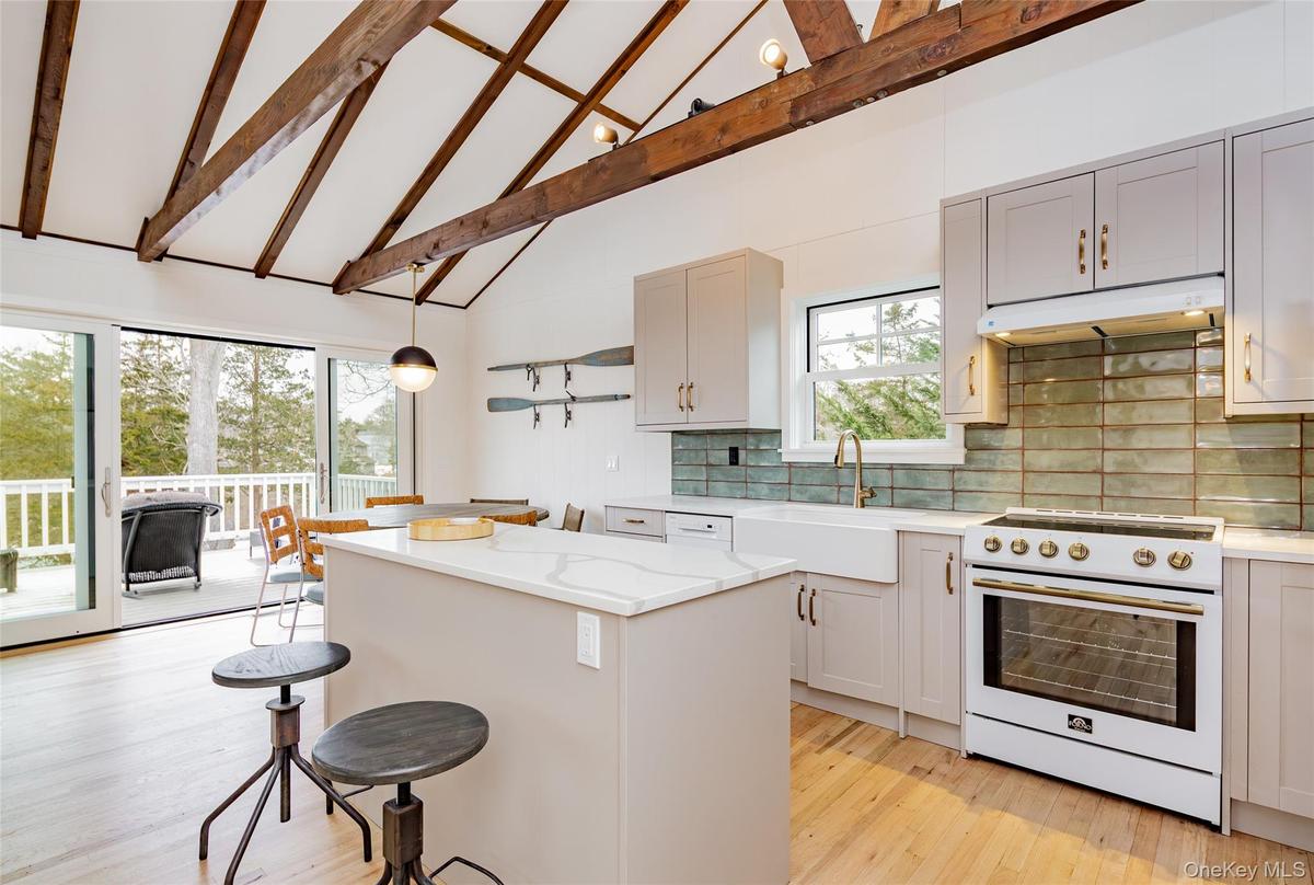 Kitchen with high vaulted ceiling, high end white range, a breakfast bar area, tasteful backsplash, and a kitchen island
