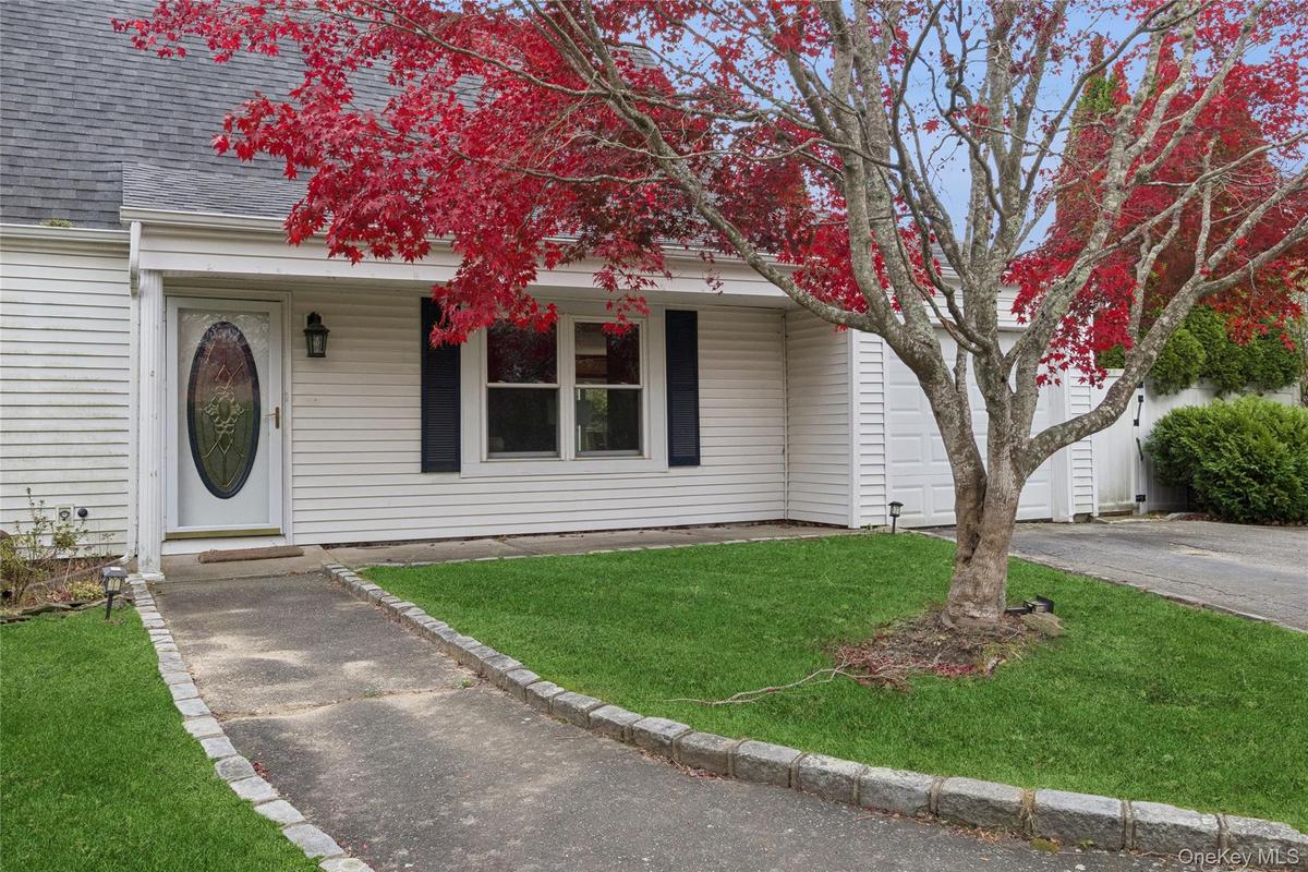 View of front of property featuring roof with shingles, a front yard, and driveway
