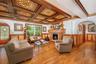 Living area with wainscoting, arched walkways, a fireplace, crown molding, and coffered ceiling