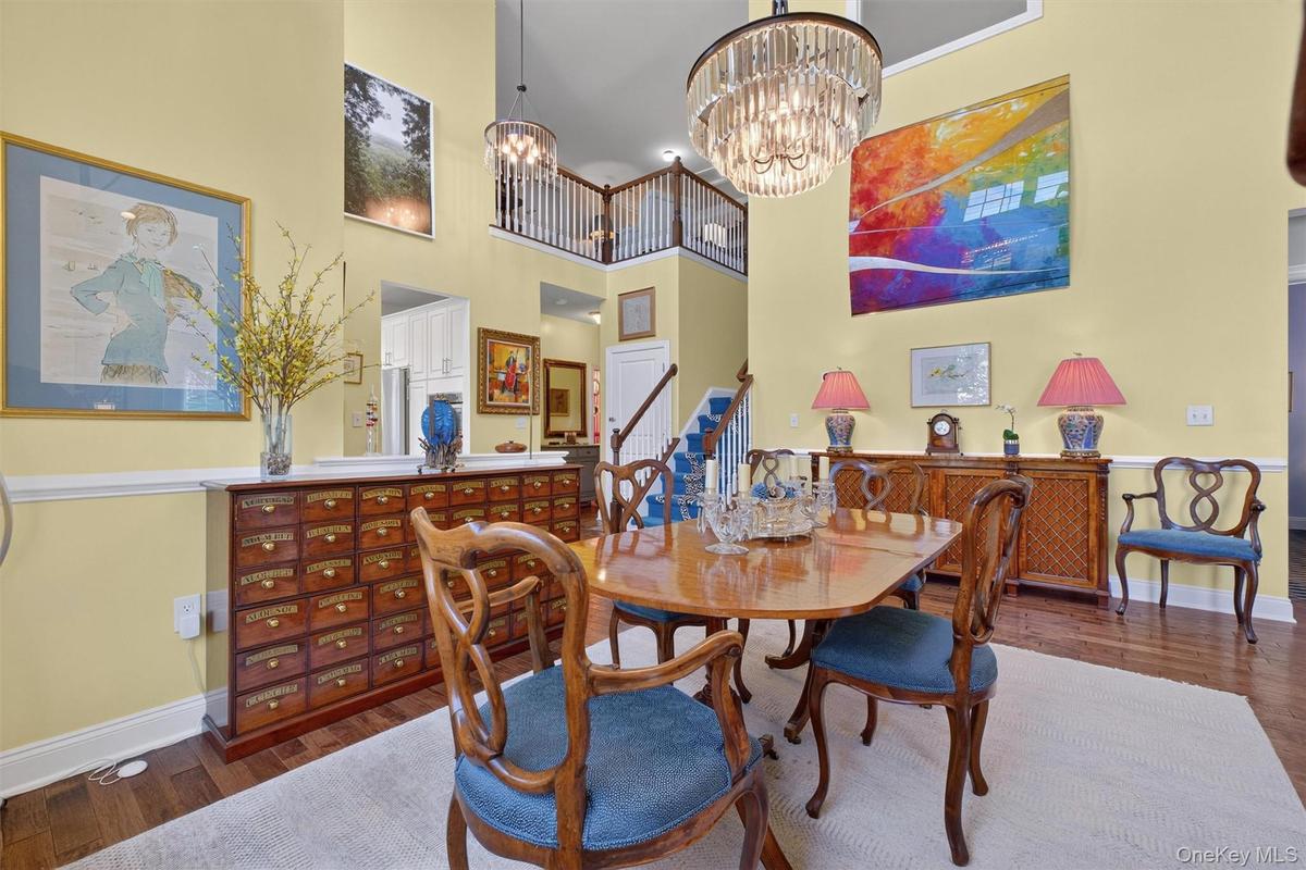 Dining room with dark wood-style flooring, a chandelier, a high ceiling, and stairway