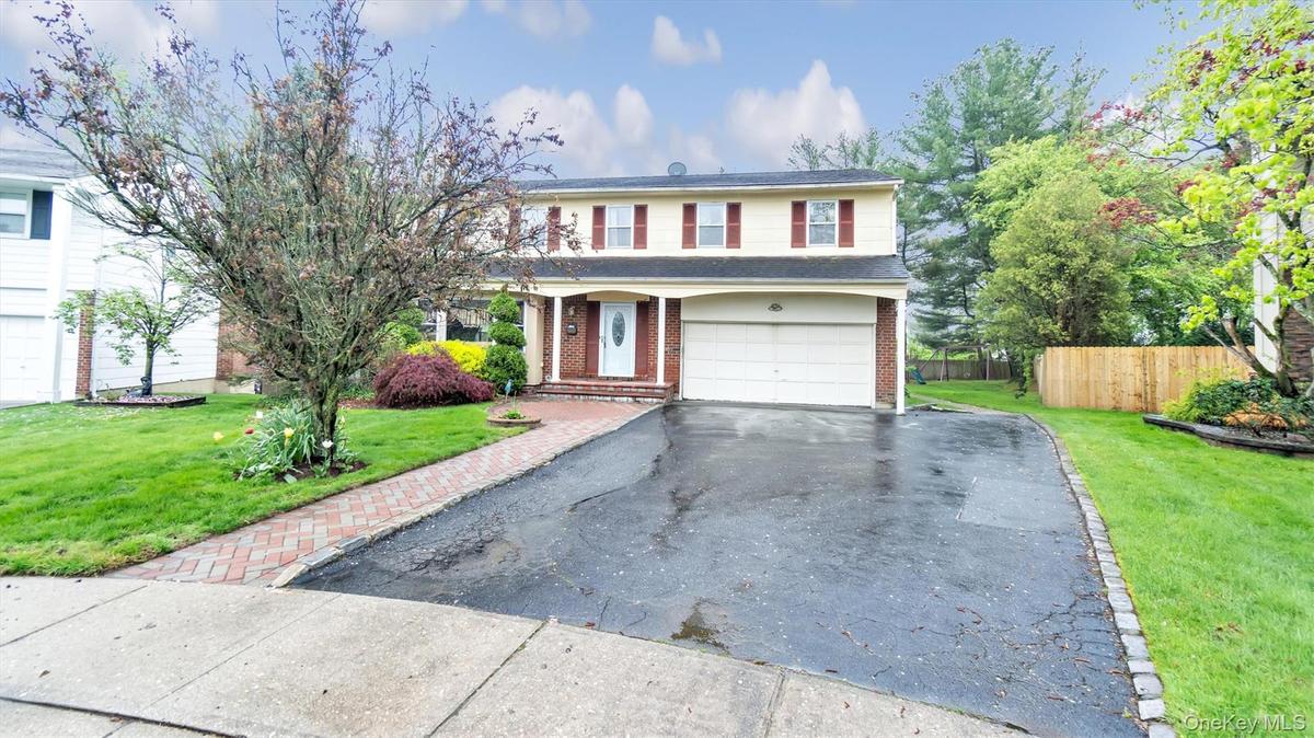 Traditional-style home featuring a garage, fence, aphalt driveway, a front yard, and brick siding