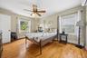 Spacious primary bedroom featuring rich hardwood flooring, multiple oversized windows that fill the room with natural light, and a generous layout off