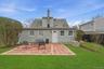 Back of house featuring a patio, roof with shingles, and a chimney