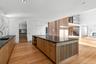 Kitchen featuring modern cabinets, a spacious island, light wood-style flooring, brown cabinetry, and dark stone counters