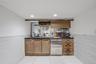 Indoor bar featuring tile walls, open shelves, a wainscoted wall, light tile patterned floors, and brown cabinetry