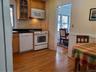 Kitchen featuring decorative backsplash, light wood-style flooring, white appliances, and glass insert cabinets