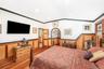 Bedroom with a wainscoted wall, light wood-style flooring, ornamental molding, and vaulted ceiling