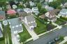 Residential neighborhood featuring a variety of architectural styles, mature trees, manicured lawns, paved driveways, and sidewalks