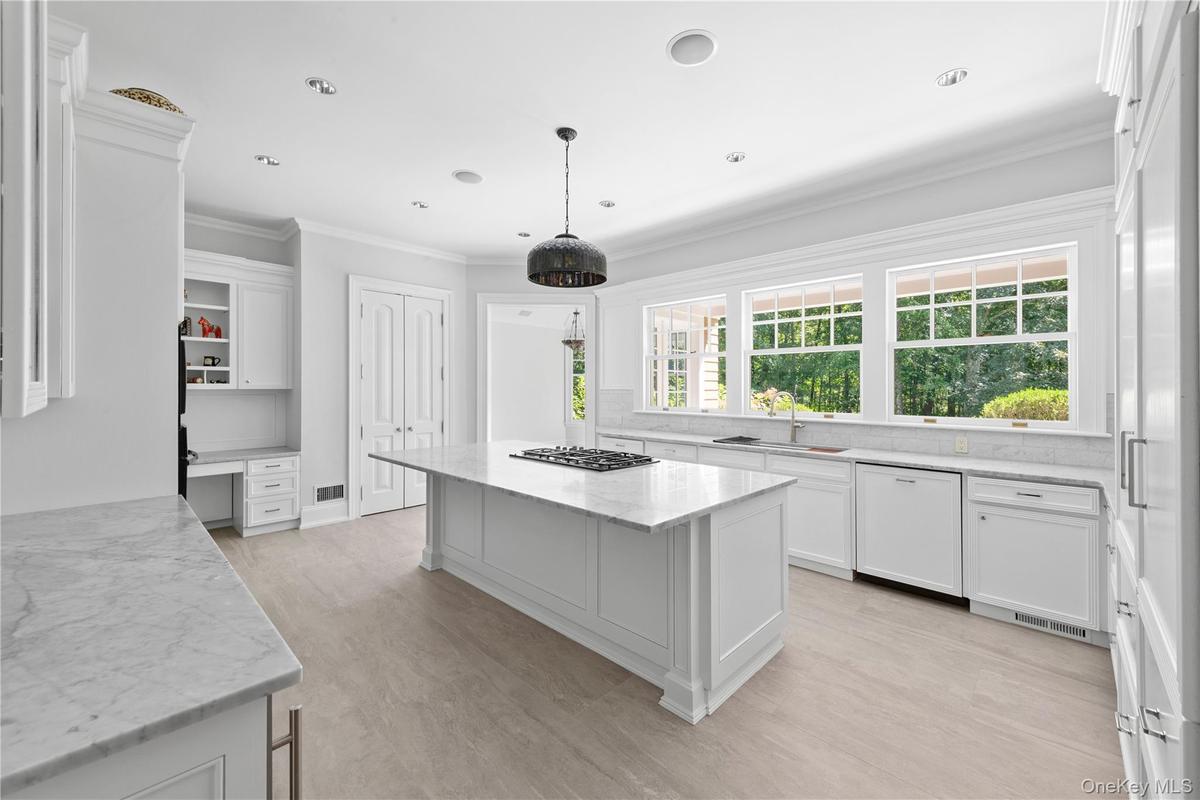 Kitchen with white cabinets, ornamental molding, light stone countertops, dishwasher, and decorative backsplash