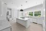 Kitchen with white cabinets, ornamental molding, light stone countertops, dishwasher, and decorative backsplash