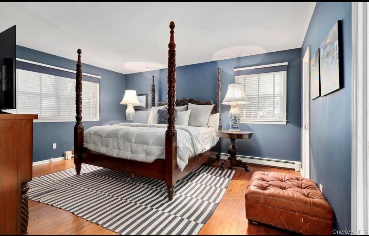 Bedroom with multiple windows, wood finished floors, and a baseboard radiator