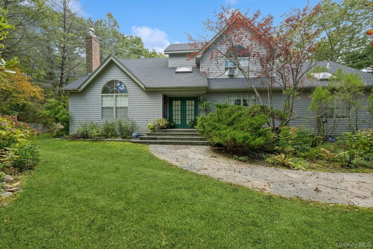 View of front of house featuring a front yard, french doors, roof with shingles, and a chimney