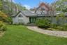 View of front of house featuring a front yard, french doors, roof with shingles, and a chimney