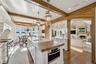 Kitchen featuring butcher block counters, decorative light fixtures, a kitchen island with sink, white cabinetry, and appliances with stainless steel 