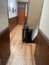 Corridor with a wainscoted wall, wooden walls, an upstairs landing, and light wood-type flooring