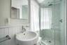 Modern bathroom featuring a glass-enclosed shower with mosaic tile surround, rainfall showerhead, and a pedestal sink with chrome fixtures