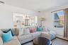 Living area with a chandelier, crown molding, a baseboard heating unit, and wood finished floors