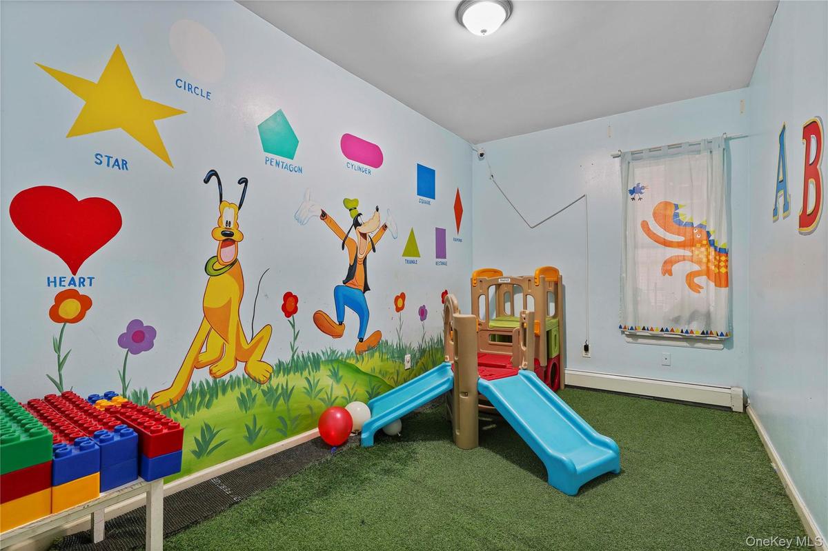 Room featuring light blue walls with colorful murals, artificial turf flooring, and a ceiling-mounted light fixture