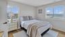 Bedroom with baseboards, visible vents, wood finished floors, and multiple windows