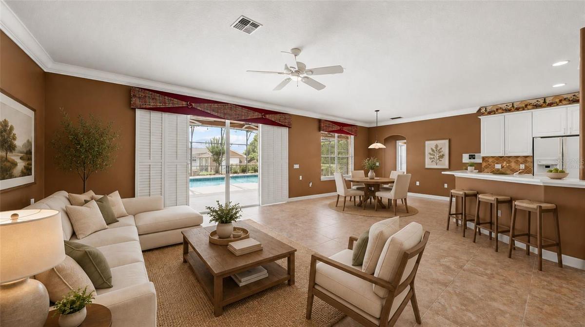 Family room, breakfast nook, & kitchen opening up to the screened lanai. (virtually staged)