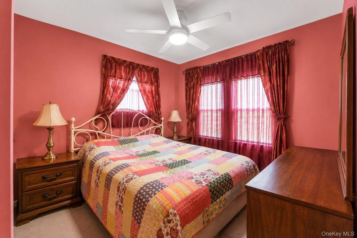 Bedroom featuring two windows with sheer and opaque drapery, a ceiling fan with integrated lighting, and a neutral-toned carpet