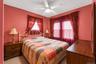 Bedroom featuring two windows with sheer and opaque drapery, a ceiling fan with integrated lighting, and a neutral-toned carpet