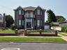 Brick exterior featuring a Juliet balcony with metal railing, arched windows, and full glass entryway with double doors.  Fenced in yard with brick an