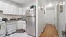 Kitchen with dark countertops, white appliances, white cabinets, a baseboard radiator, and range hood