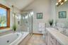 Full bathroom with vaulted ceiling, a bath, vanity, a stall shower, and light tile patterned floors