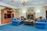 Living area in the clubhouse, featuring a fireplace, crown molding, a chandelier, and a wainscoted wall