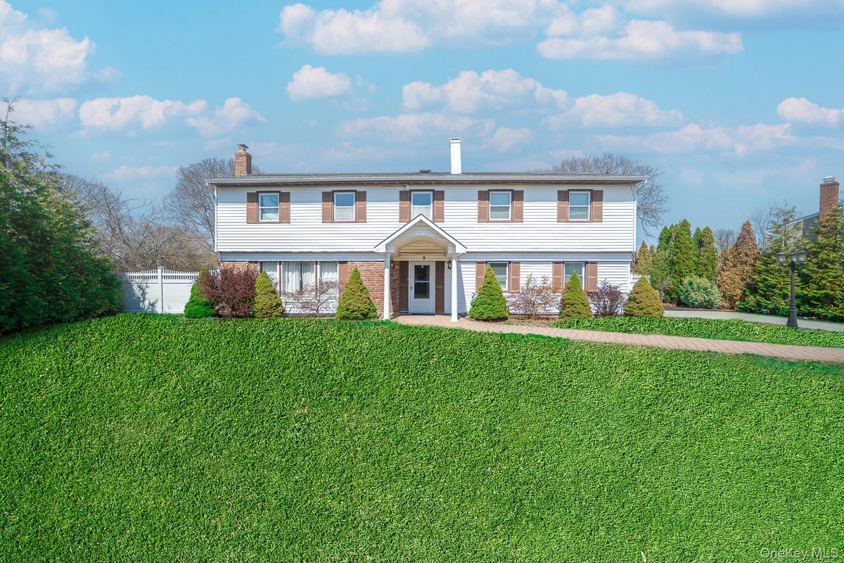 Colonial inspired home with a chimney, a front lawn, and fence