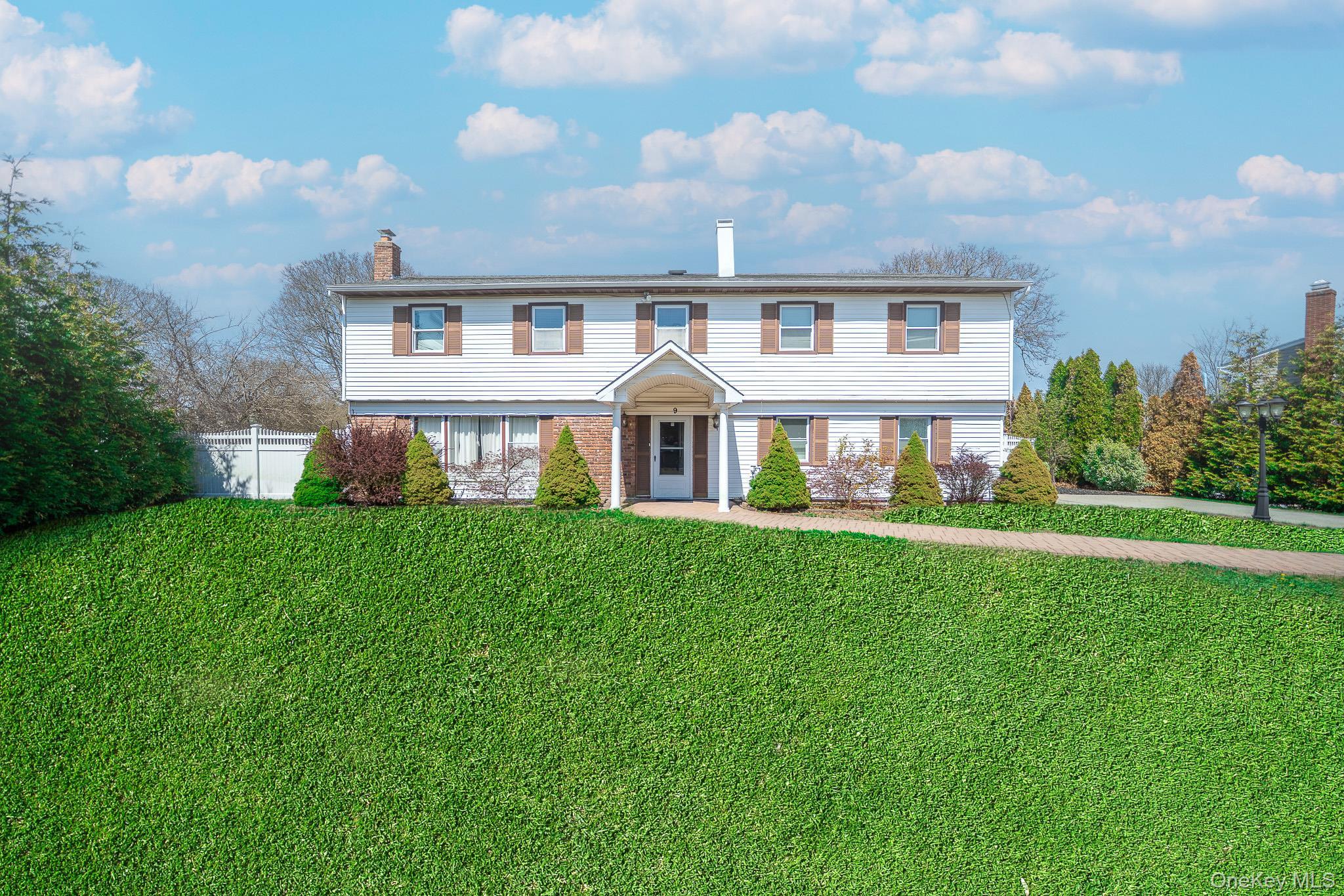 Colonial inspired home with a chimney, a front lawn, and fence
