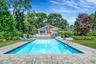 Swimming pool with a patio, a yard, and view of scattered trees