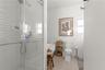 Full bathroom featuring healthy amount of natural light, a stall shower, toilet, a wainscoted wall, and tile walls