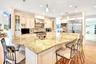 Kitchen with glass insert cabinets, cream cabinets, a kitchen bar, recessed lighting, and crown molding
