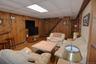 Recreation room featuring wood paneling, wood-finish flooring, drop ceiling with flush lighting, and a visible staircase