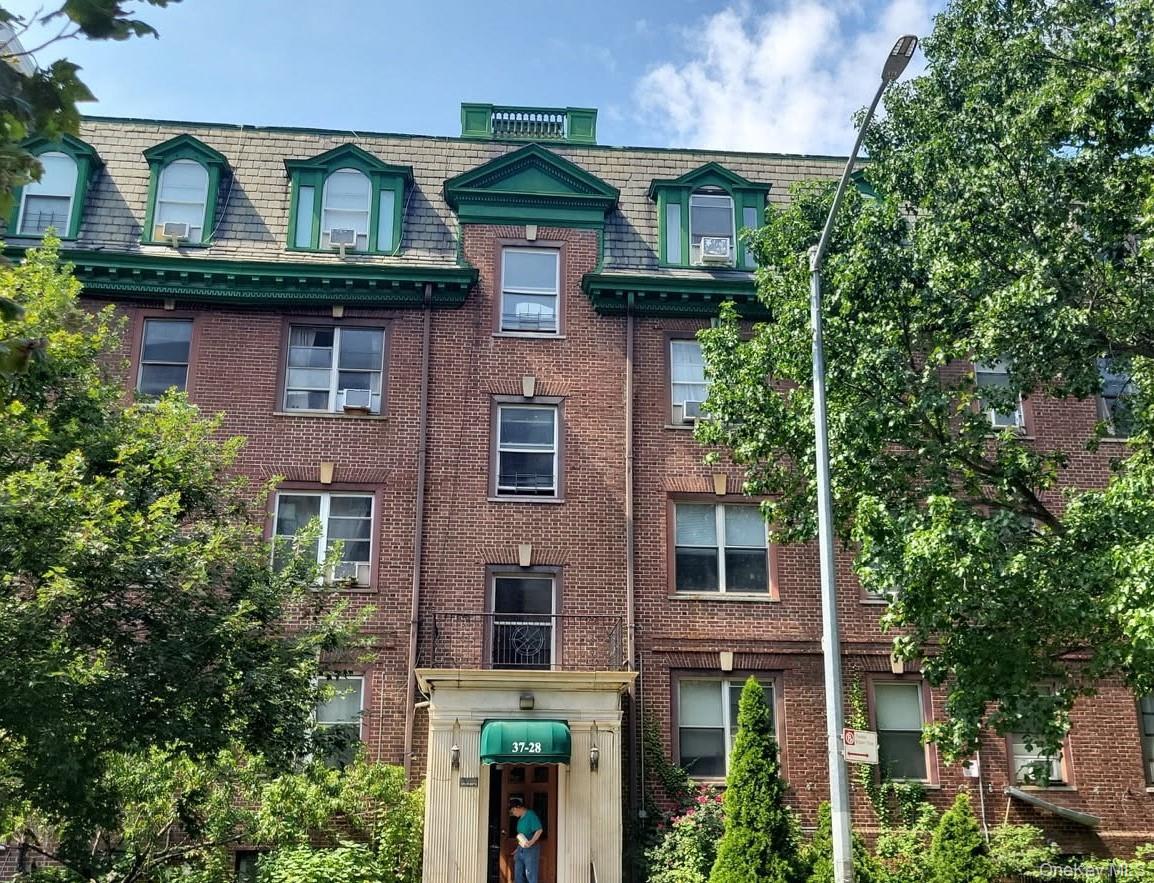 Brick facade with decorative green trim, arched dormer windows, and a prominent entrance canopy
