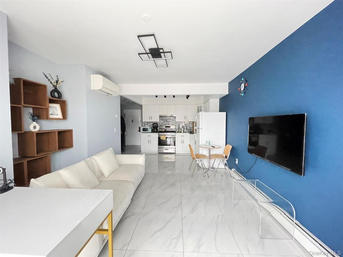 Living area with a baseboard radiator, light marble finish floors, and a wall mounted AC
